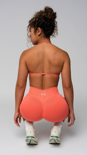 Woman in a peach MG set, back view, studio.